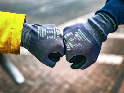 Zwei Personen mit Handschuhen stoßen Fäuste zusammen, symbolisieren Teamgeist, Begrüßung oder Zusammenarbeit Zwei Personen mit Handschuhen stoßen Fäuste zusammen, symbolisieren Teamgeist, Begrüßung oder Zusammenarbeit