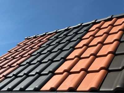Dach mit Ziegeln in Rot, Grau und Braun unter blauem Himmel zeigt Vielfalt an Materialien für Dachdeckung Dach mit Ziegeln in Rot, Grau und Braun unter blauem Himmel zeigt Vielfalt an Materialien für Dachdeckung