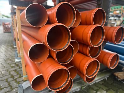Gestapelte orange Kunststoffrohre lagern draußen, zeigen Materialien für unterirdische Infrastrukturprojekte Gestapelte orange Kunststoffrohre lagern draußen, zeigen Materialien für unterirdische Infrastrukturprojekte