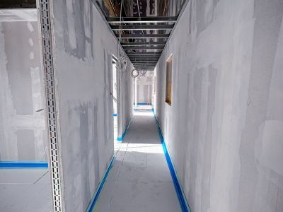 Rohbauflur mit unverputzten Wänden und Kabeln an Decke, zeigt Innenausbauphase mit sichtbarer Technikstruktur Rohbauflur mit unverputzten Wänden und Kabeln an Decke, zeigt Innenausbauphase mit sichtbarer Technikstruktur