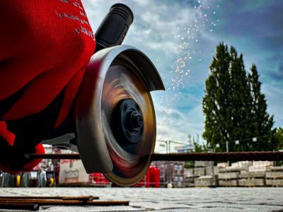 Winkelschleifer schneidet Metallstäbe, Funken fliegen, zeigt Einsatz von Maschinen im Bauhandwerk draußen Winkelschleifer schneidet Metallstäbe, Funken fliegen, zeigt Einsatz von Maschinen im Bauhandwerk draußen