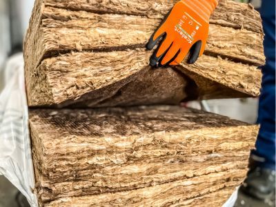 Person mit Handschuhen hält dicke Dämmmatte, zeigt thermische Isolierung mit Mineralwolle oder Glasfaser Person mit Handschuhen hält dicke Dämmmatte, zeigt thermische Isolierung mit Mineralwolle oder Glasfaser