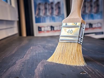 Pinsel liegt auf dunklem Holz, zeigt Anwendung von Farben oder Lasuren im Innenbereich Pinsel liegt auf dunklem Holz, zeigt Anwendung von Farben oder Lasuren im Innenbereich